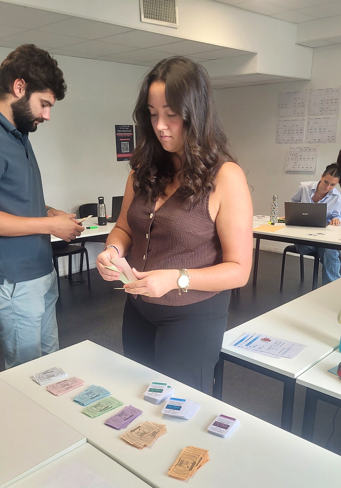 Participants manipulant les cartes et les billets d'un jeu pédagogique Onidea